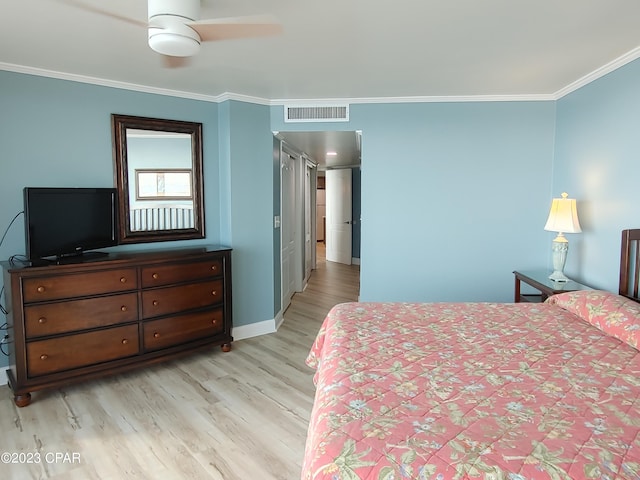 bedroom featuring light wood finished floors, ornamental molding, visible vents, and baseboards