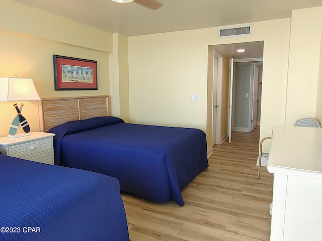 bedroom with light wood finished floors, baseboards, visible vents, and a ceiling fan