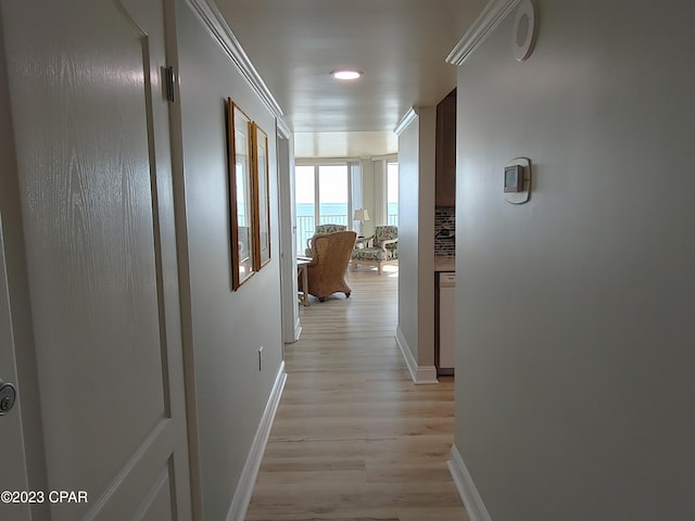 corridor featuring baseboards and light wood finished floors