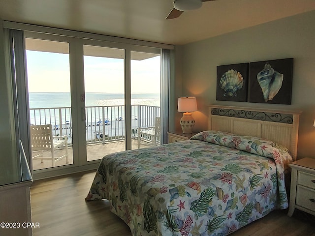 bedroom with a water view, access to exterior, and wood finished floors