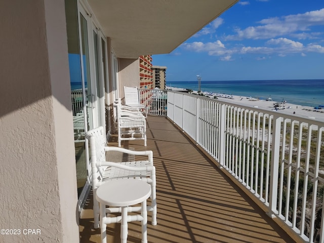 balcony featuring a view of the beach and a water view