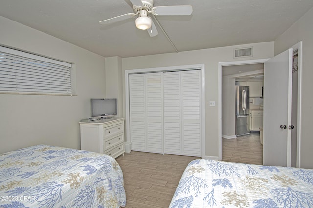 bedroom featuring ceiling fan, stainless steel refrigerator, and a closet