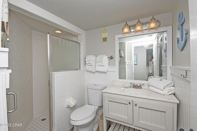 bathroom with vanity, toilet, a shower with door, and a textured ceiling