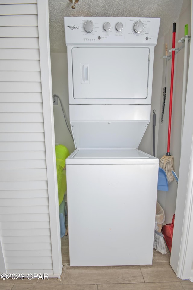 laundry room with stacked washer and clothes dryer, a textured ceiling, and light hardwood / wood-style flooring