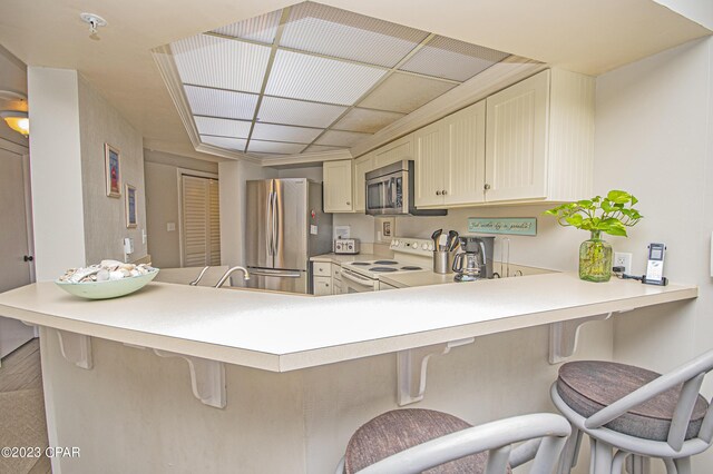 kitchen featuring a kitchen bar, kitchen peninsula, and appliances with stainless steel finishes