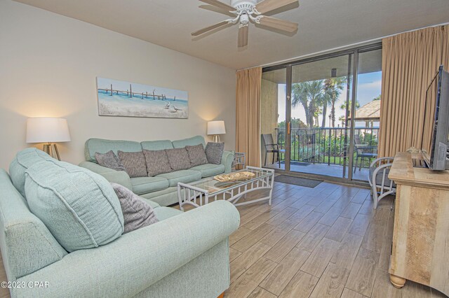 living room with floor to ceiling windows, wood-type flooring, and ceiling fan