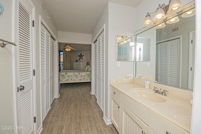 bathroom with hardwood / wood-style flooring, vanity, a textured ceiling, and ceiling fan