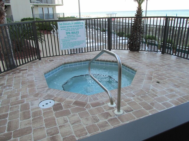 view of swimming pool with a water view and a hot tub