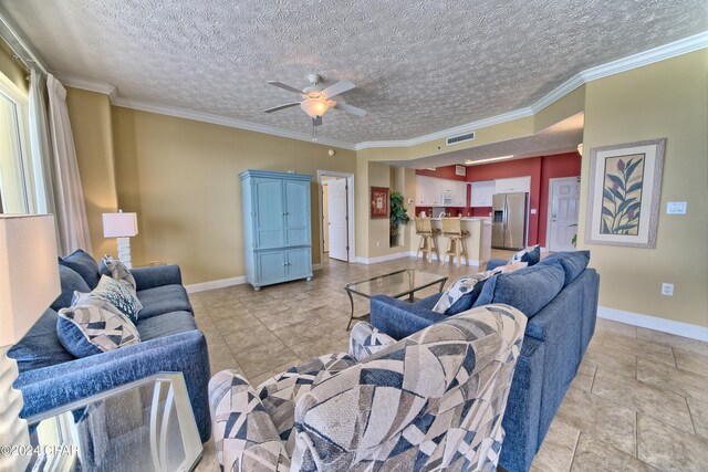 living room featuring crown molding, ceiling fan, and a textured ceiling