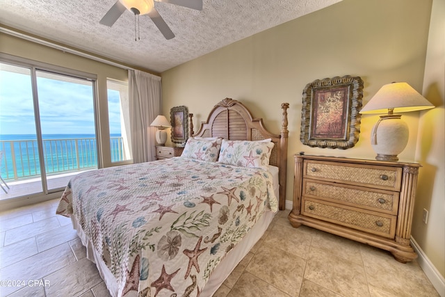 bedroom with light tile patterned flooring, a water view, a textured ceiling, ceiling fan, and access to exterior