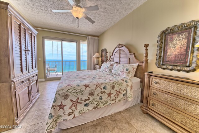 bedroom featuring a water view, a textured ceiling, light tile patterned floors, ceiling fan, and access to exterior