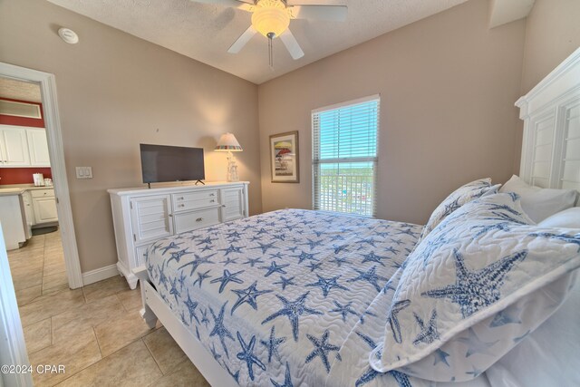 bedroom with light tile patterned floors, a textured ceiling, and ceiling fan