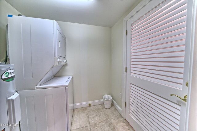 laundry room featuring stacked washer / drying machine and light tile patterned floors