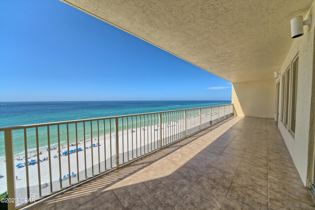 balcony featuring a view of the beach and a water view