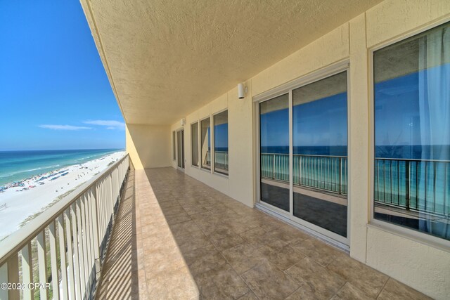 balcony featuring a view of the beach and a water view