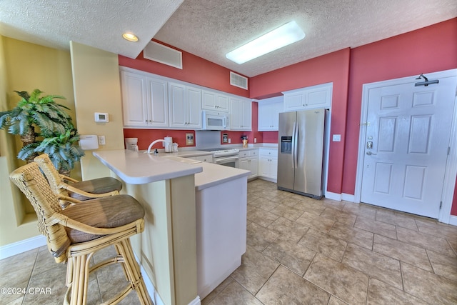 kitchen featuring a breakfast bar, white cabinetry, sink, kitchen peninsula, and white appliances