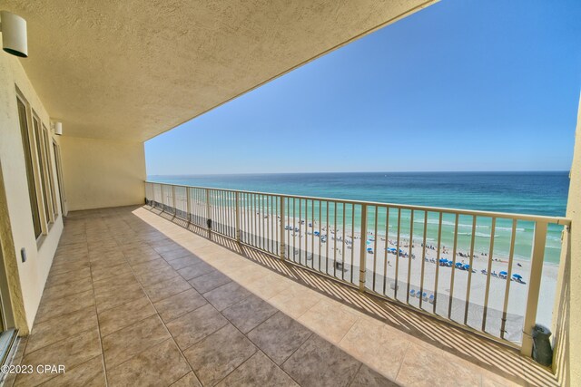 balcony featuring a view of the beach and a water view