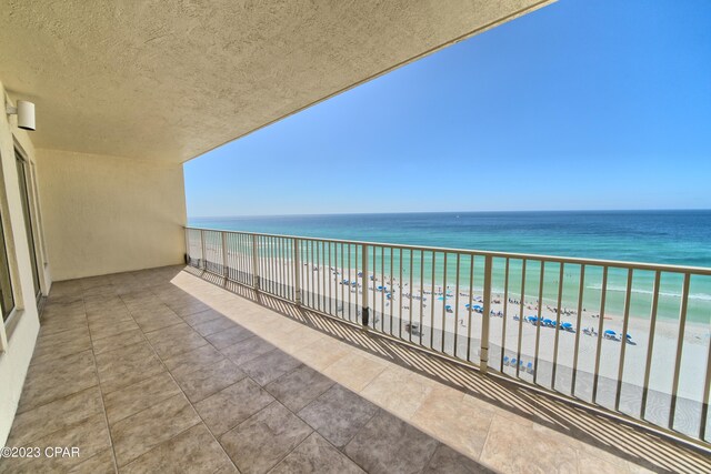 balcony with a water view and a view of the beach