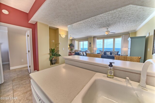 kitchen with ceiling fan, sink, a textured ceiling, and light tile patterned floors