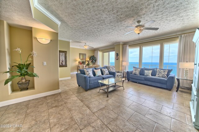 living room featuring a water view, ceiling fan, ornamental molding, and a textured ceiling