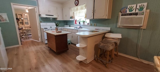 kitchen featuring a breakfast bar area, white range with electric cooktop, and light wood-type flooring