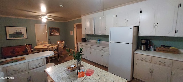 kitchen with white refrigerator, ceiling fan, ornamental molding, white cabinetry, and dark hardwood / wood-style flooring