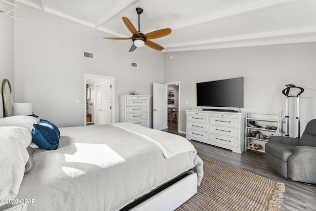 bedroom featuring beam ceiling, wooden ceiling, ceiling fan, dark wood-type flooring, and a towering ceiling