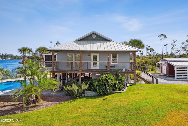 back of property featuring a lawn, a swimming pool side deck with water view, and a storage shed