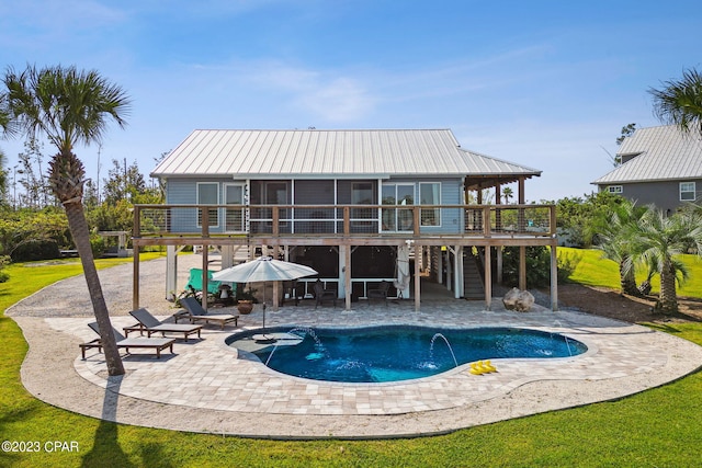 rear view of house with a lawn, a swimming pool side deck, and a patio area