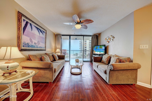 living room with expansive windows, ceiling fan, dark wood-type flooring, and a textured ceiling