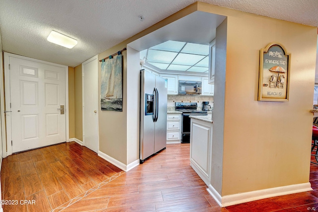 corridor with light hardwood / wood-style floors and a textured ceiling