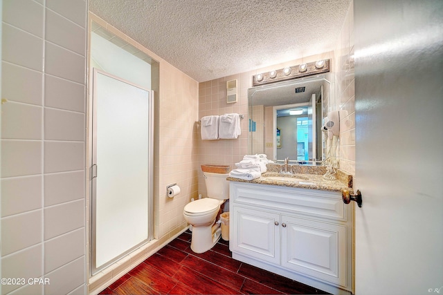 bathroom featuring tile walls, hardwood / wood-style floors, vanity, a textured ceiling, and walk in shower