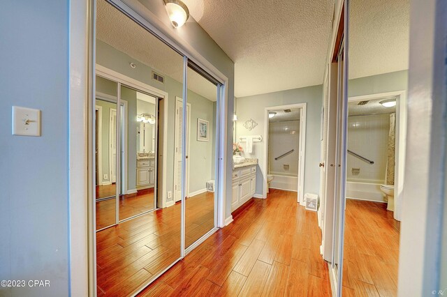 hall with light hardwood / wood-style flooring and a textured ceiling