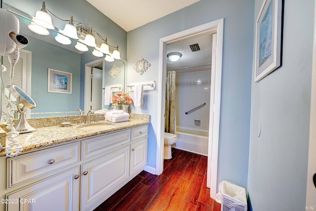 full bathroom with wood-type flooring, vanity, toilet, shower / bathtub combination with curtain, and a textured ceiling