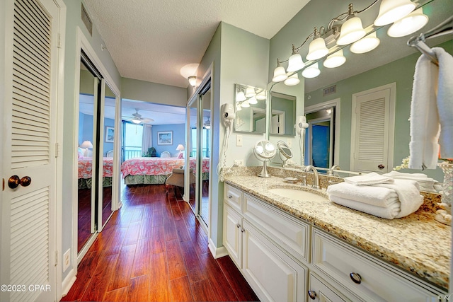 bathroom with ceiling fan, wood-type flooring, a textured ceiling, and vanity