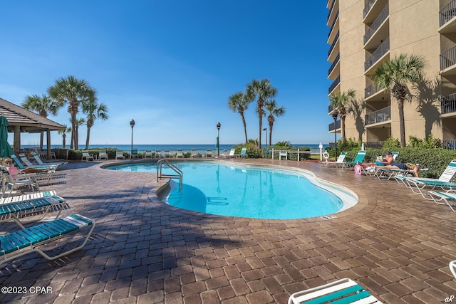 view of swimming pool featuring a patio and a water view