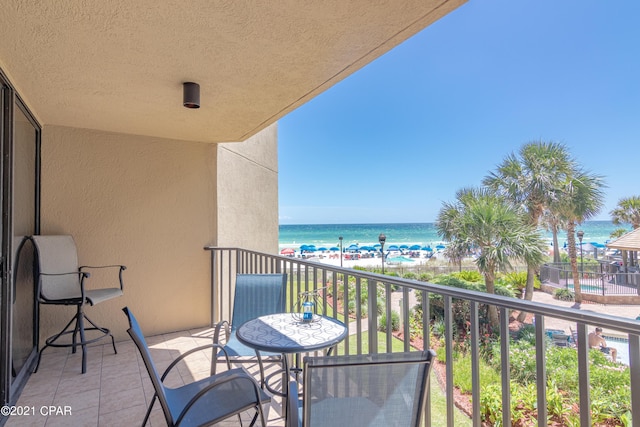 balcony with a water view and a view of the beach