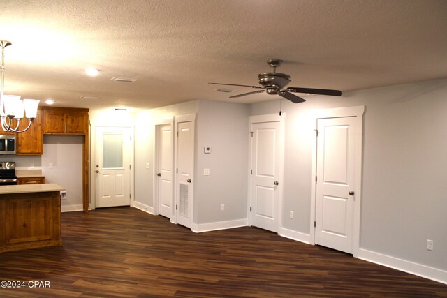 interior space with a textured ceiling, ceiling fan with notable chandelier, stainless steel appliances, and dark wood-type flooring