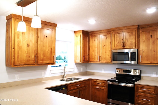 kitchen with pendant lighting, sink, appliances with stainless steel finishes, and a textured ceiling