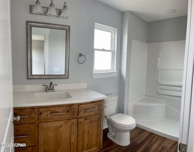 bathroom with wood-type flooring, vanity, toilet, and walk in shower