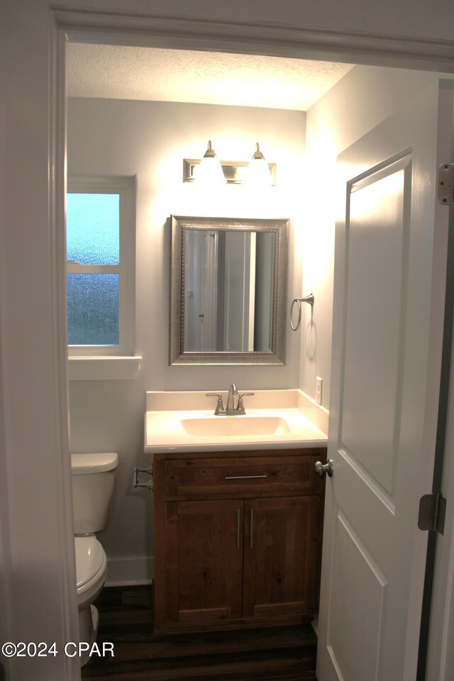 bathroom with hardwood / wood-style flooring, vanity, a textured ceiling, and toilet