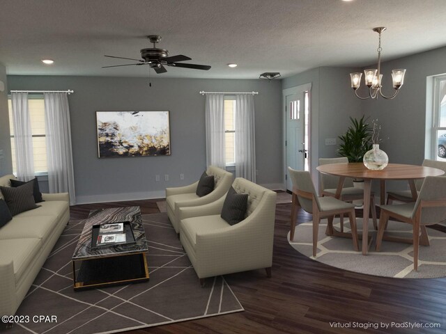 living room featuring a textured ceiling, ceiling fan with notable chandelier, and dark wood-type flooring