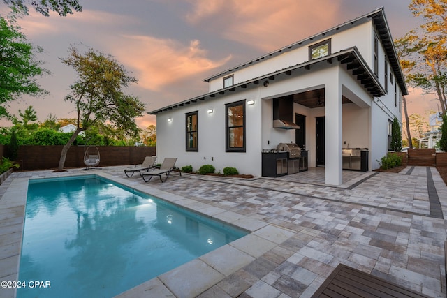 pool at dusk featuring a patio, area for grilling, and a grill