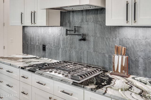 kitchen with backsplash, white cabinets, and light stone countertops