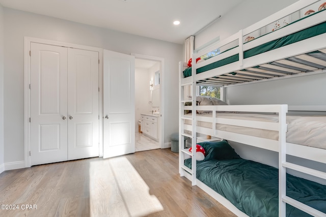 bedroom with a closet, ensuite bath, and light wood-type flooring