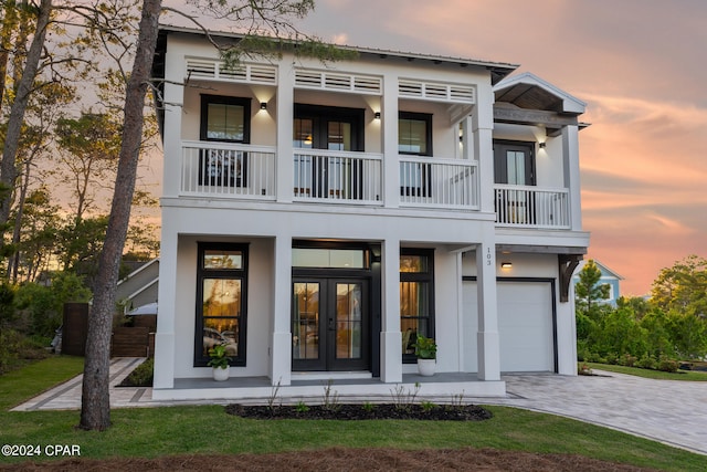 view of front facade with a garage, french doors, and a balcony