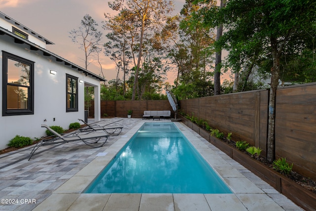 pool at dusk with a patio area