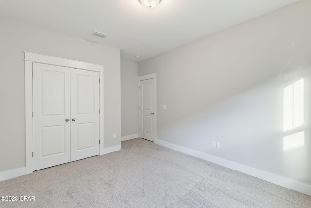 unfurnished bedroom with light carpet and a closet