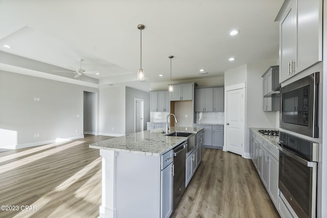 kitchen featuring a center island with sink, sink, ceiling fan, gray cabinets, and stainless steel appliances