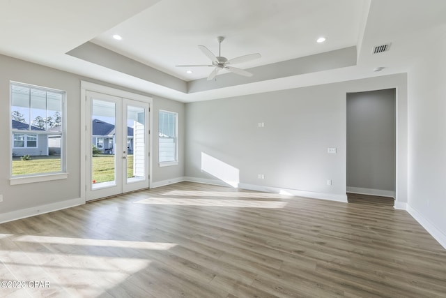 spare room featuring ceiling fan, a healthy amount of sunlight, french doors, and a tray ceiling